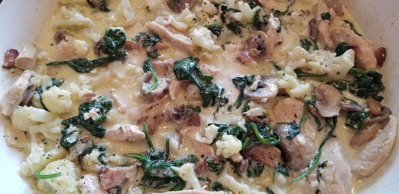Yummy keto cauliflower chicken Alfredo simmering on the stove. Creamy