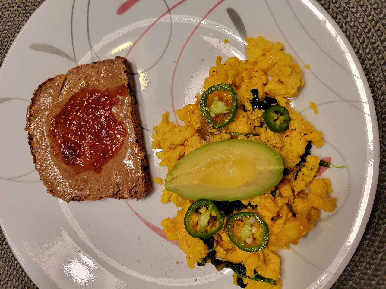 Breakfast. Scrambled eggs with cheese and some spinach, almond butter